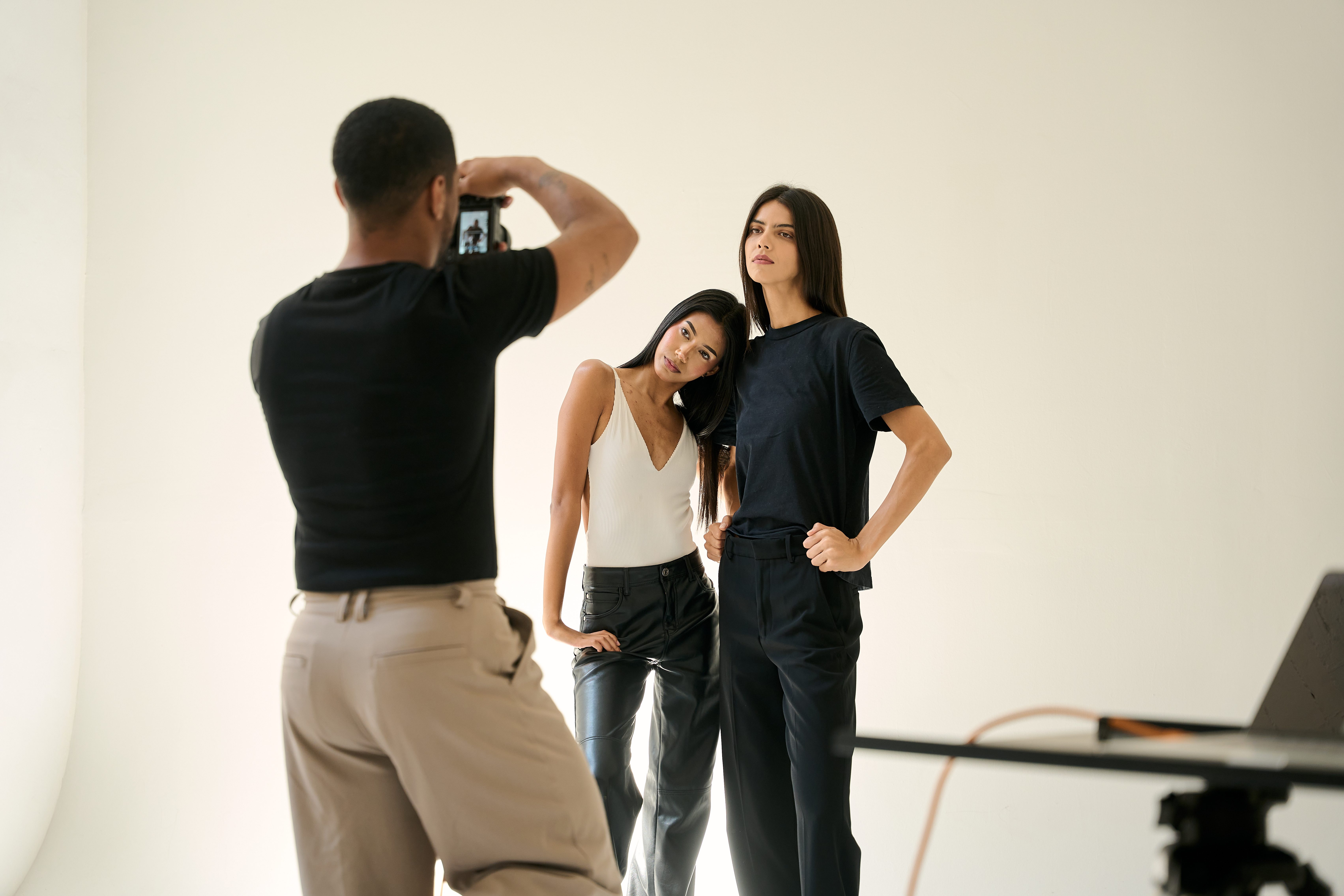 A photographer taking a photo of two models in an all white room